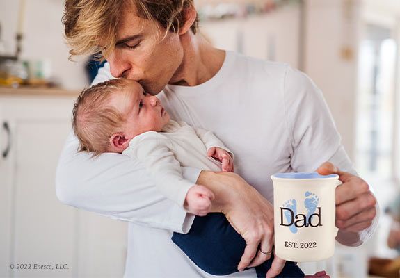 Father Kissing Baby with Mug