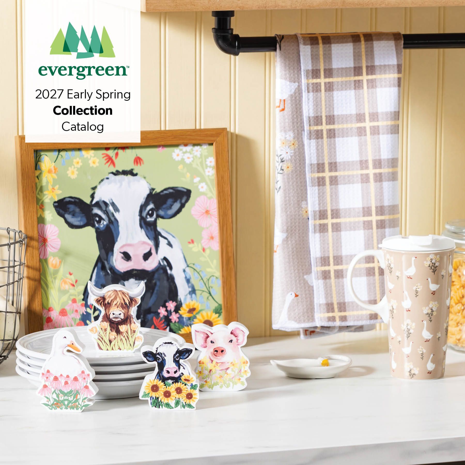 Evergreen 2027 Early Spring Collection Catalog – farmhouse kitchen vignette with cow artwork, farm animal figurines, plaid tea towels, and goose-print travel mug