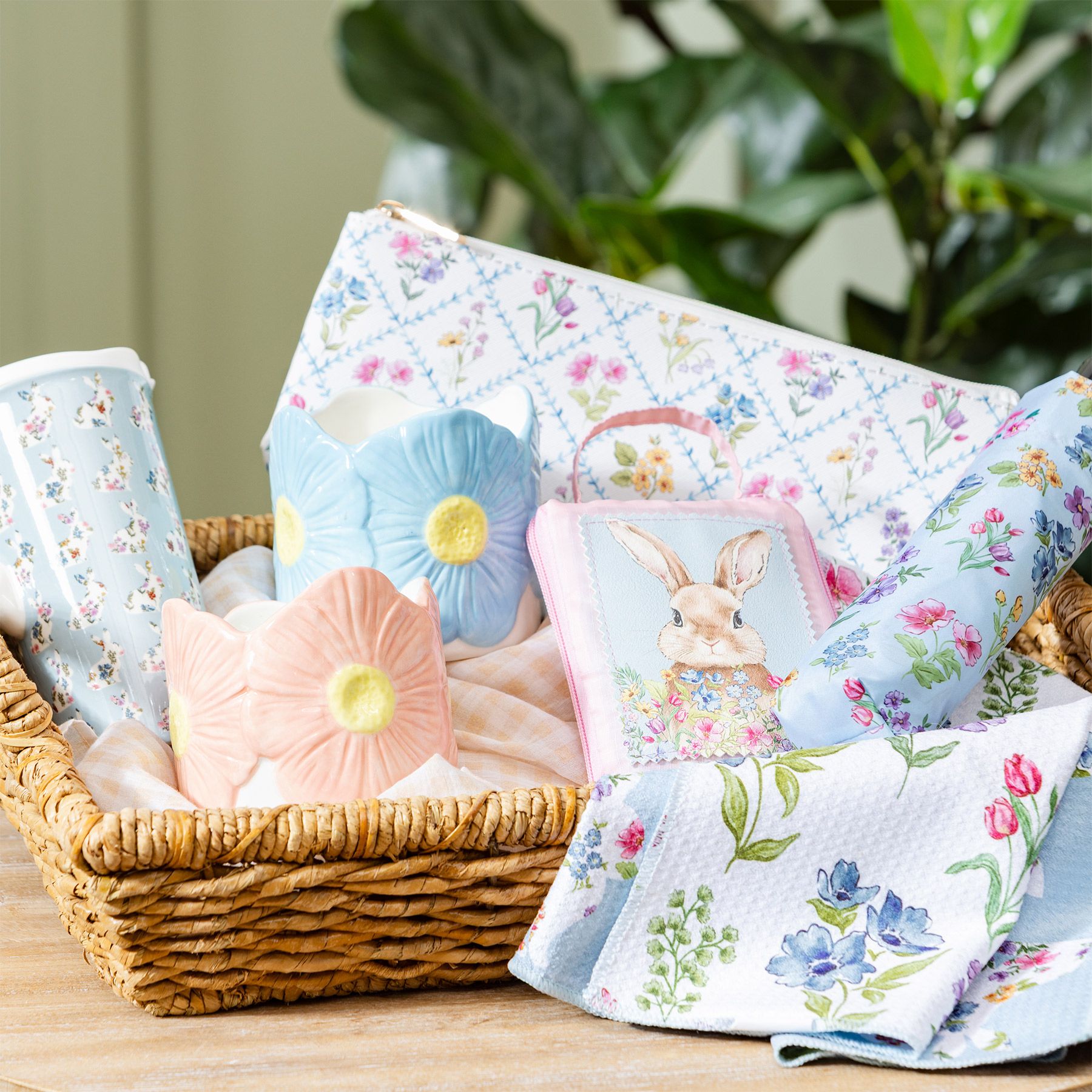Hop Into Spring collection with pastel daisy-shaped ceramic vases, bunny pouch, floral towels, and spring accessories in a woven basket
