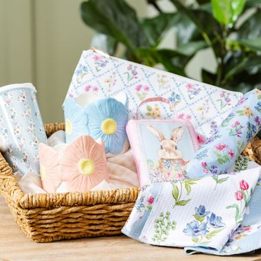 Hop Into Spring collection with pastel daisy-shaped ceramic vases, bunny pouch, floral towels, and spring accessories in a woven basket