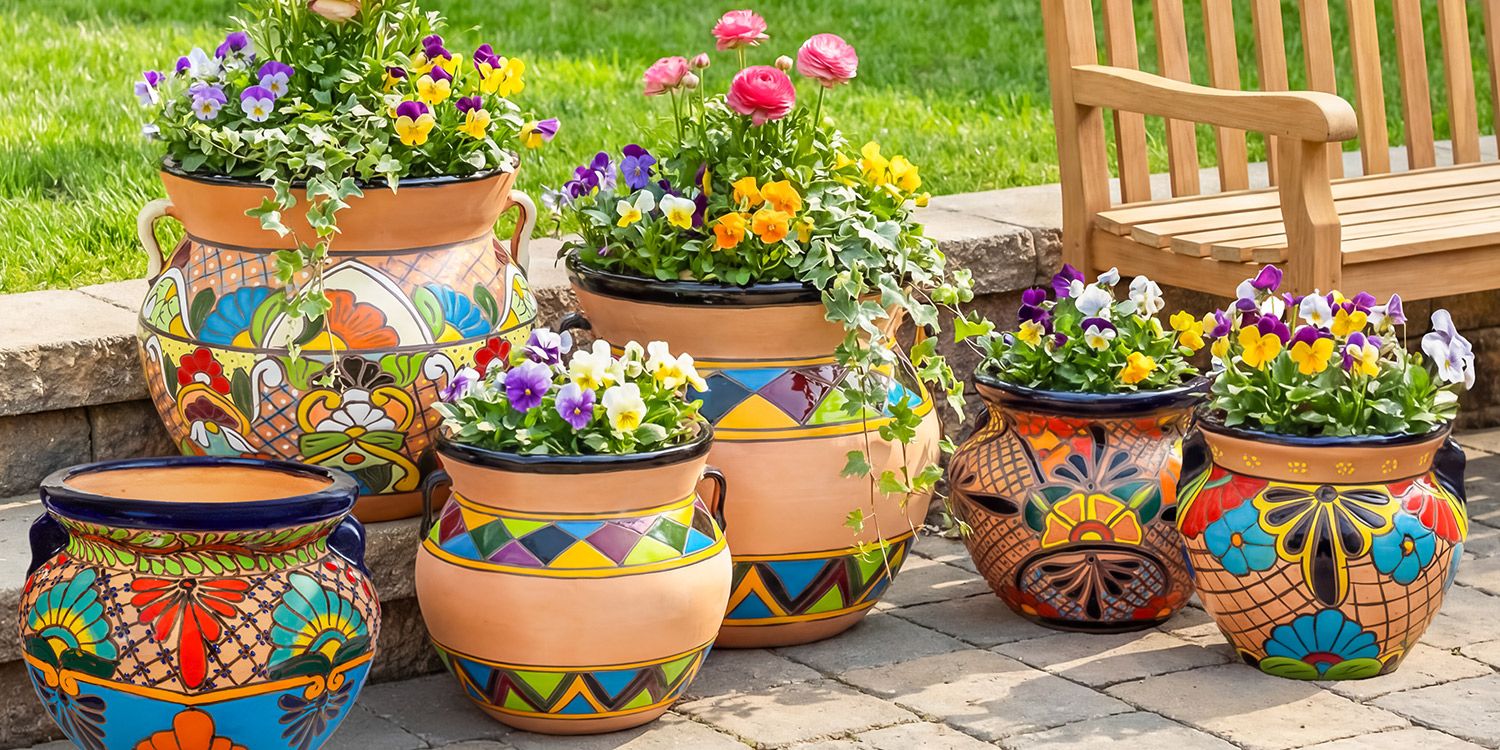 Colorful hand-painted Talavera-style ceramic planters filled with pansies, ranunculus, and ivy on a stone patio