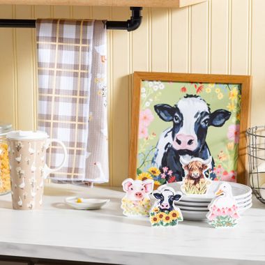 Hillside Pasture collection with farmhouse cow framed art, pig, cow, highland cow, and goose figurines, plaid towel, and goose-print travel mug