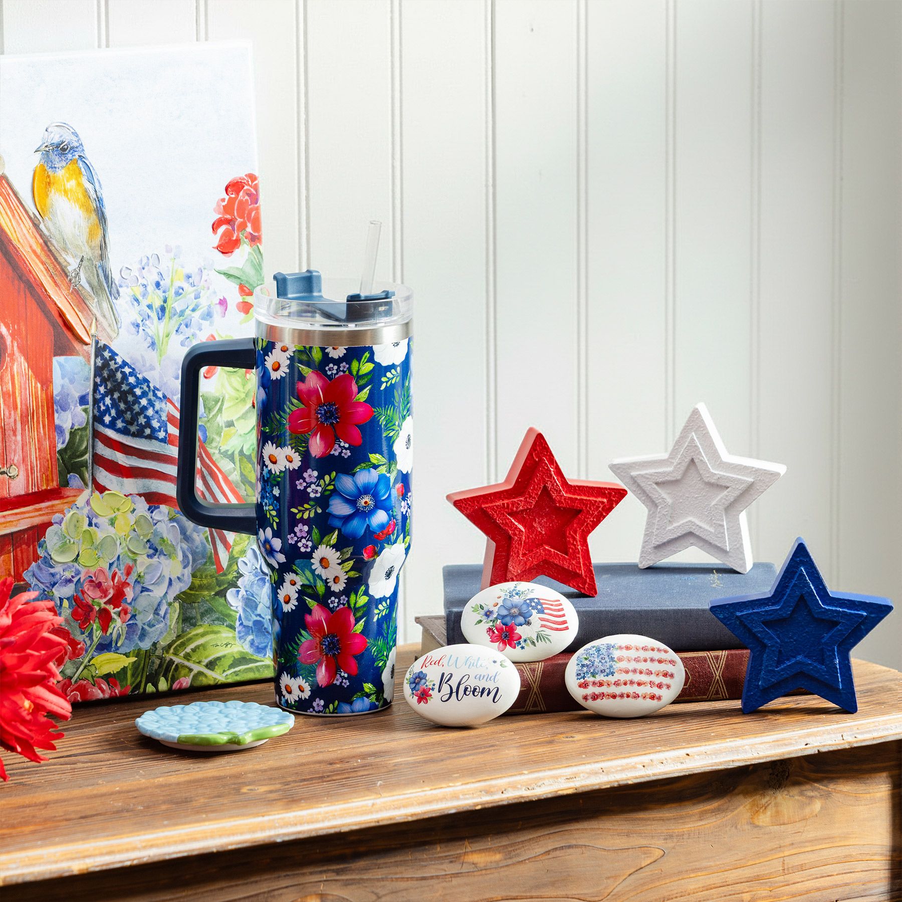 Red White and Bloom patriotic collection featuring floral tumbler, painted stones, red white and blue wooden stars, and birdhouse flag art