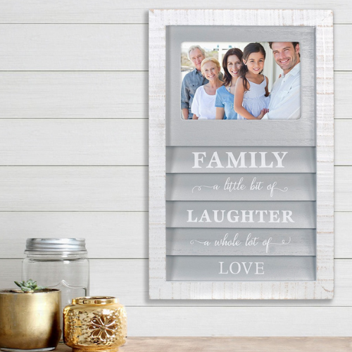 Wall-mounted photo frame with a smiling multigenerational family picture and the words “Family – a little bit of laughter – a whole lot of love” inscribed below.