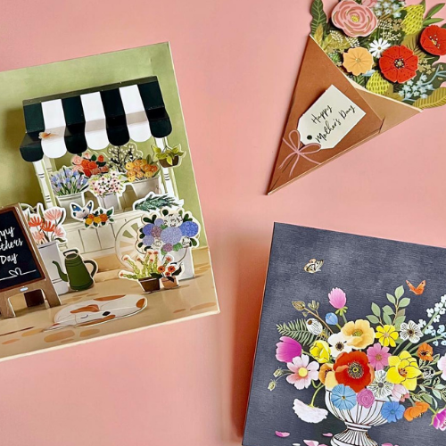 Three intricately designed Mother’s Day pop-up cards on a pink background, each showcasing detailed floral arrangements in different artistic styles.