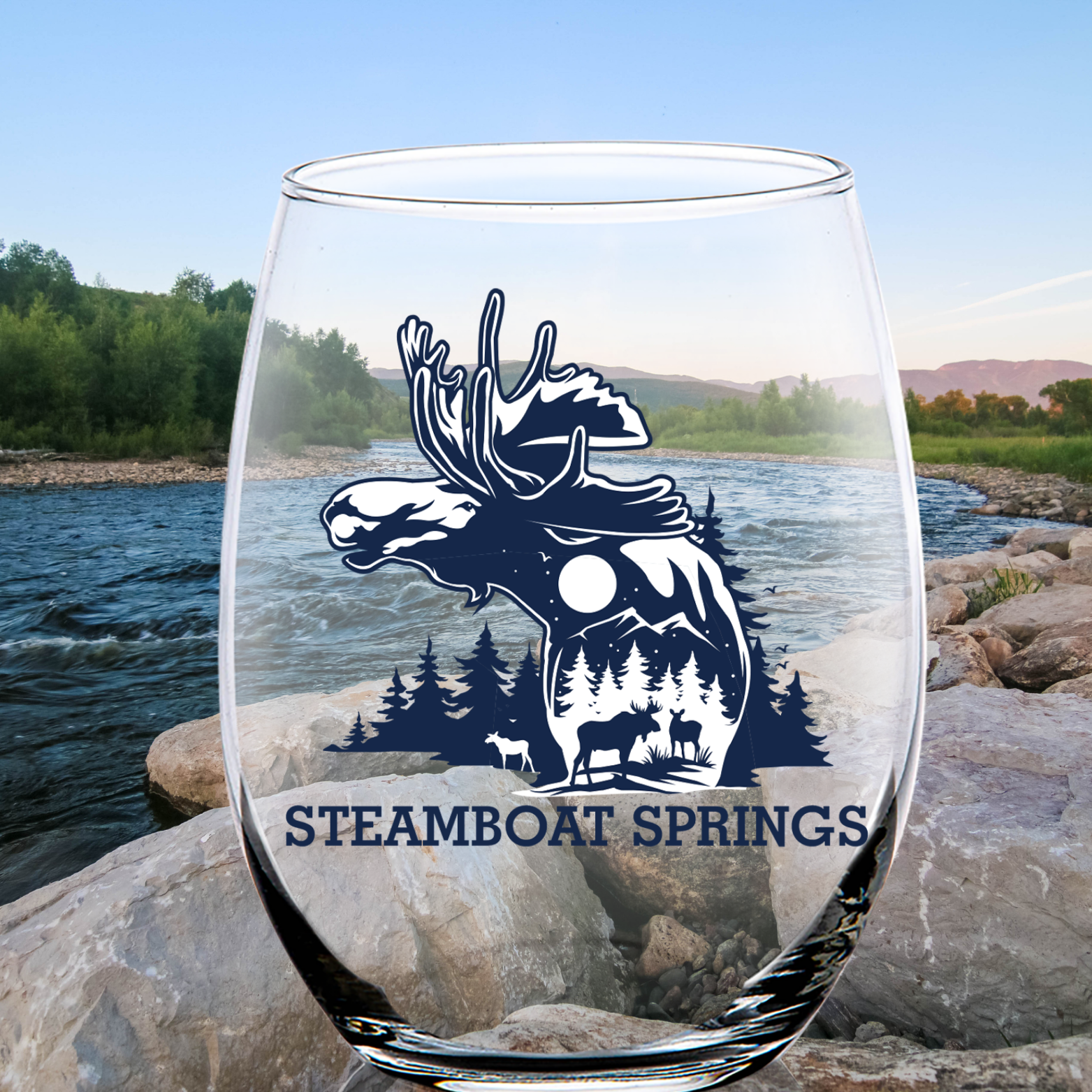 Clear stemless wine glass featuring a silhouette design of a moose, forest, and wildlife with the text “Steamboat Springs,” set against a scenic river and mountain backdrop.